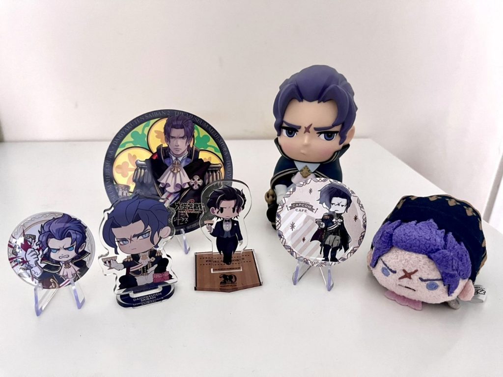 Examples of ‘character goods’ of Barok van Zieks, a character from The Great Ace Attorney by Capcom. The ‘goods’ come in various formats such as badges, coasters, acrylic stands and plushies, and can be official or fan-made. Author’s collection.